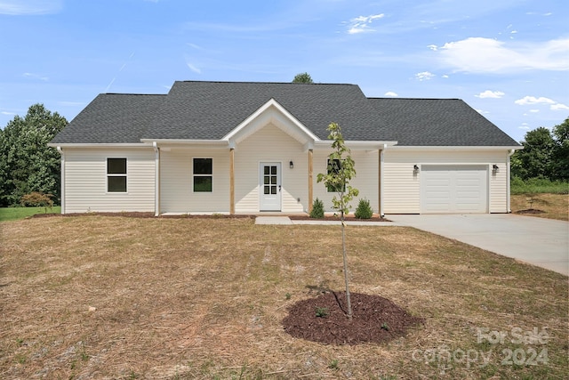 view of front of home featuring an attached garage, driveway, roof with shingles, and a front yard