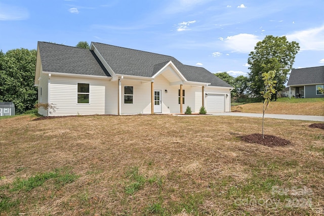 view of front of property featuring a garage, roof with shingles, concrete driveway, and a front yard