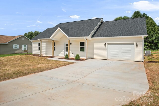 view of front of house with central air condition unit, a front yard, and a garage