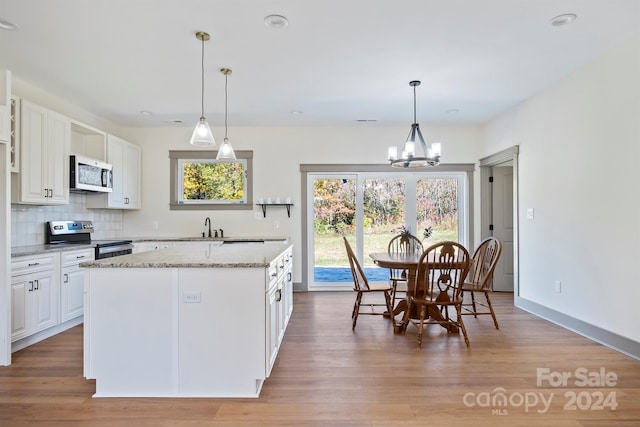 kitchen with stainless steel appliances, white cabinets, a kitchen island, and decorative light fixtures