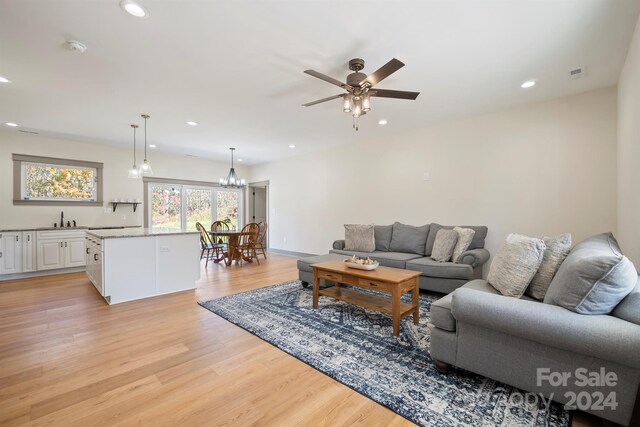 living area with recessed lighting, visible vents, light wood finished floors, and ceiling fan with notable chandelier