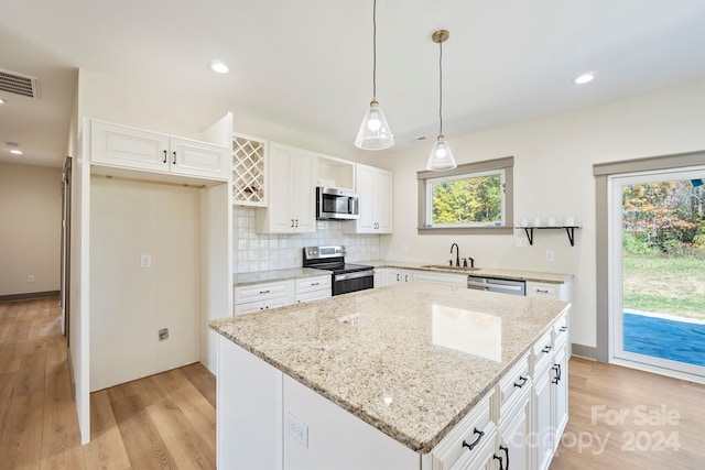 kitchen with hanging light fixtures, appliances with stainless steel finishes, white cabinetry, and a center island