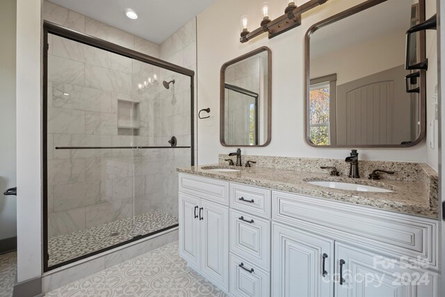 full bathroom featuring double vanity, a stall shower, and a sink