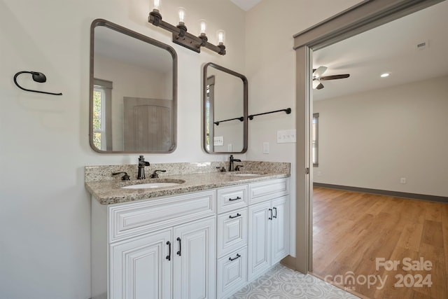 full bathroom featuring double vanity, baseboards, a sink, and wood finished floors