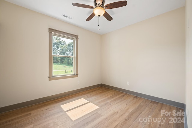 empty room with ceiling fan, light wood finished floors, visible vents, and baseboards