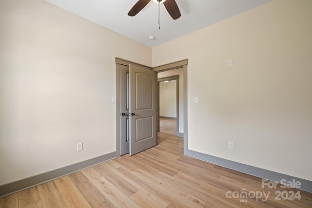 empty room featuring light wood finished floors, ceiling fan, and baseboards