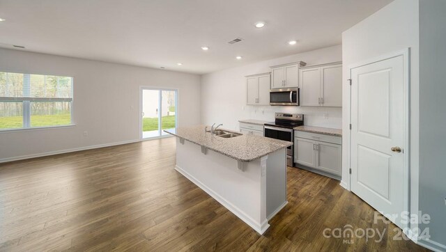 kitchen featuring decorative backsplash, dark hardwood / wood-style flooring, appliances with stainless steel finishes, sink, and a breakfast bar area