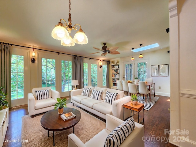 living room with ceiling fan with notable chandelier, dark hardwood / wood-style flooring, and plenty of natural light