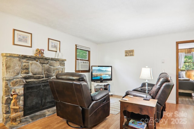 living room with cooling unit, a fireplace, and light hardwood / wood-style flooring