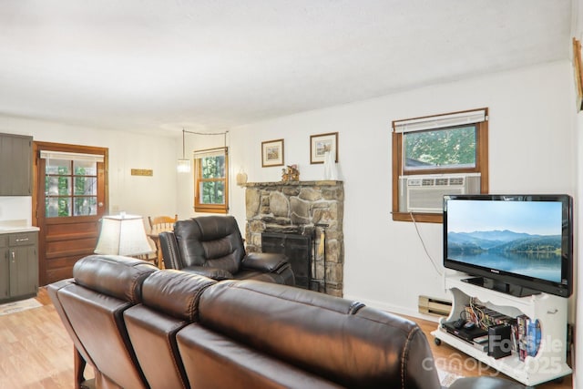 living room featuring cooling unit, a baseboard radiator, a fireplace, and light hardwood / wood-style floors