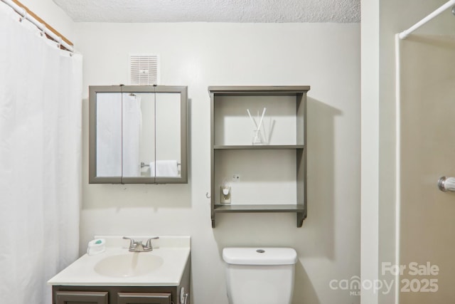 bathroom featuring walk in shower, vanity, toilet, and a textured ceiling