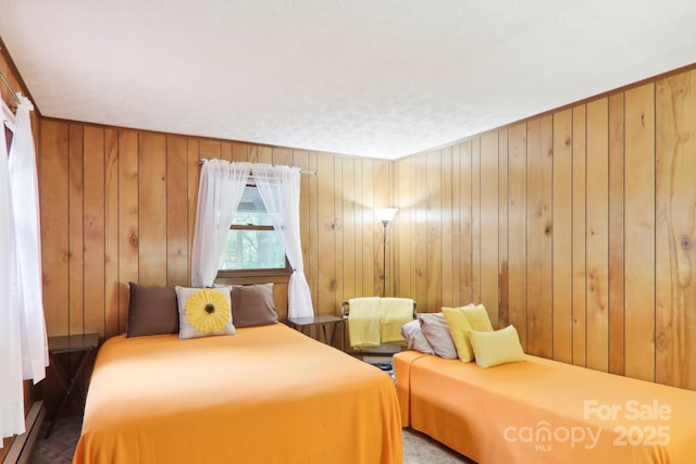 bedroom with baseboard heating and wooden walls