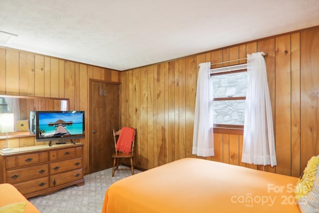 bedroom with light carpet and wood walls