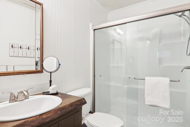 bathroom with walk in shower, vanity, crown molding, and toilet