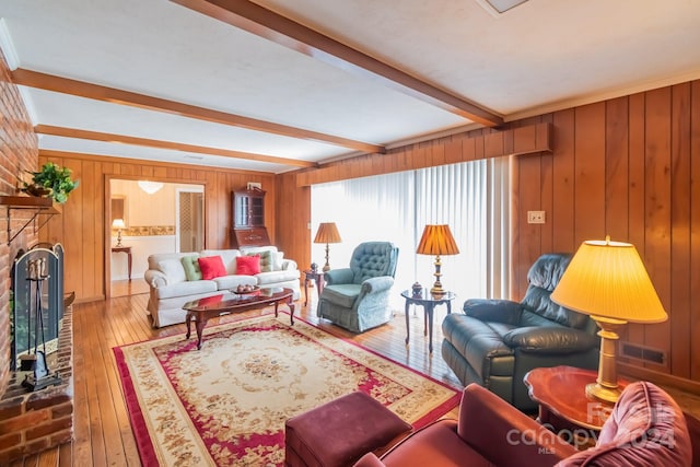 living room with wood walls, hardwood / wood-style floors, brick wall, beamed ceiling, and a fireplace