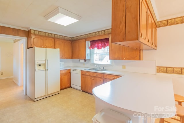 kitchen with white appliances, brown cabinets, a kitchen breakfast bar, light countertops, and a sink