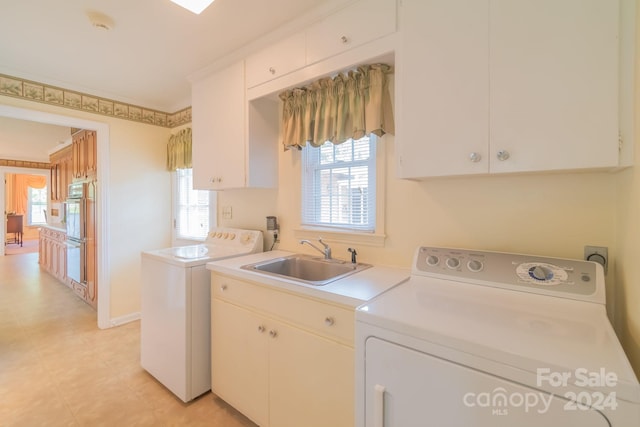 laundry room featuring independent washer and dryer, a sink, cabinet space, and baseboards