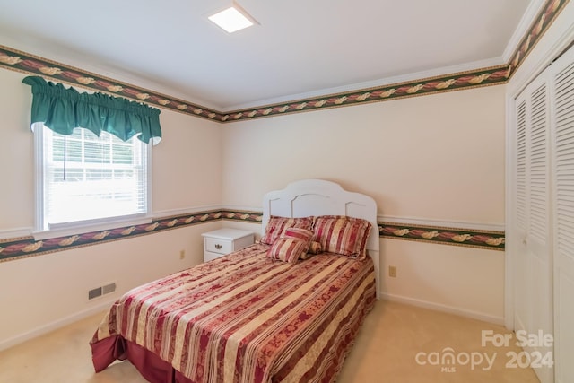 bedroom featuring light carpet, baseboards, visible vents, and a closet