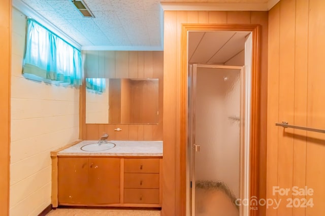 bathroom with wood walls, a shower stall, and vanity