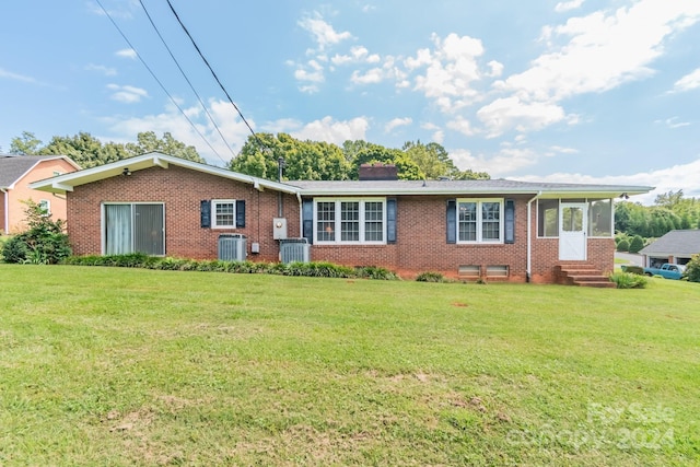 ranch-style house featuring a sunroom, brick siding, a front lawn, and central air condition unit