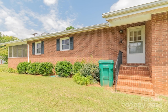 property entrance featuring a lawn and brick siding