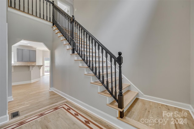 stairway with a towering ceiling and hardwood / wood-style floors