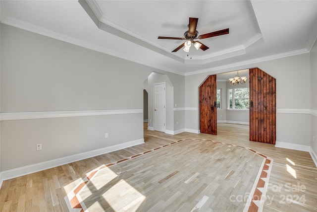 interior space with light wood-type flooring, a raised ceiling, ceiling fan with notable chandelier, and ornamental molding