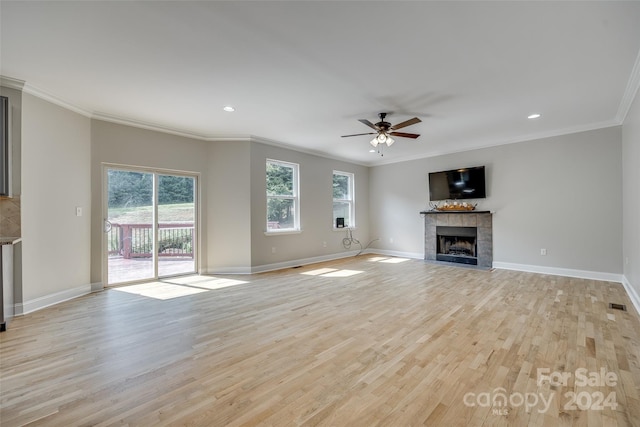 unfurnished living room with ceiling fan, crown molding, light wood-type flooring, and a tiled fireplace