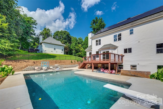 view of pool with a wooden deck, a patio area, and a diving board