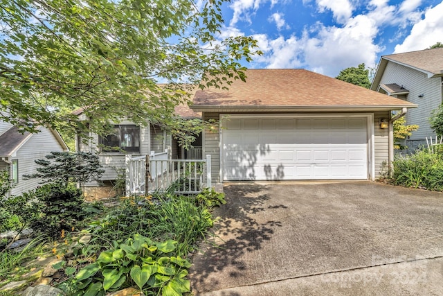 view of front facade featuring a garage, concrete driveway, and roof with shingles