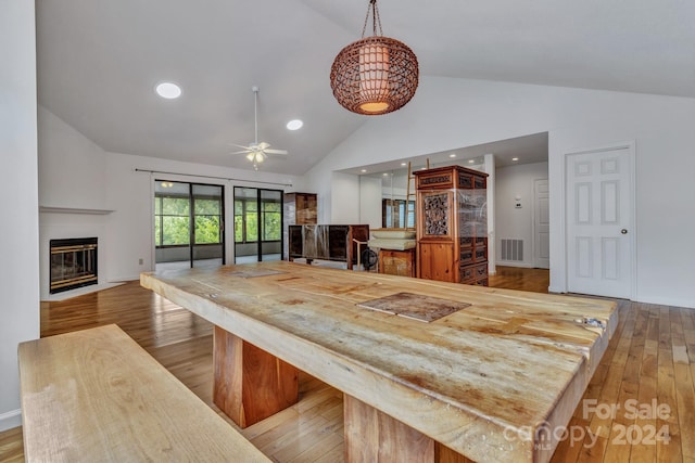 dining area featuring recessed lighting, visible vents, light wood-style flooring, a fireplace with flush hearth, and high vaulted ceiling