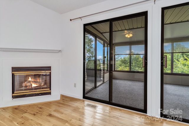 doorway to outside featuring a glass covered fireplace, wood finished floors, and visible vents