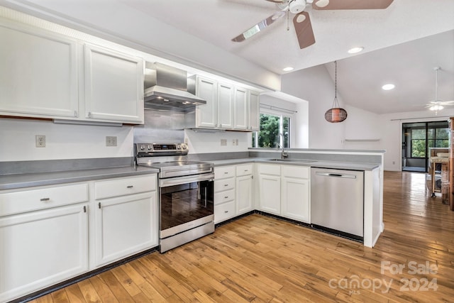 kitchen with stainless steel appliances, white cabinets, a sink, and wall chimney exhaust hood