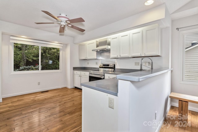 kitchen featuring visible vents, white cabinets, dark countertops, stainless steel range with electric cooktop, and wall chimney range hood