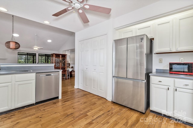 kitchen featuring white cabinets, light wood-style flooring, appliances with stainless steel finishes, hanging light fixtures, and a sink