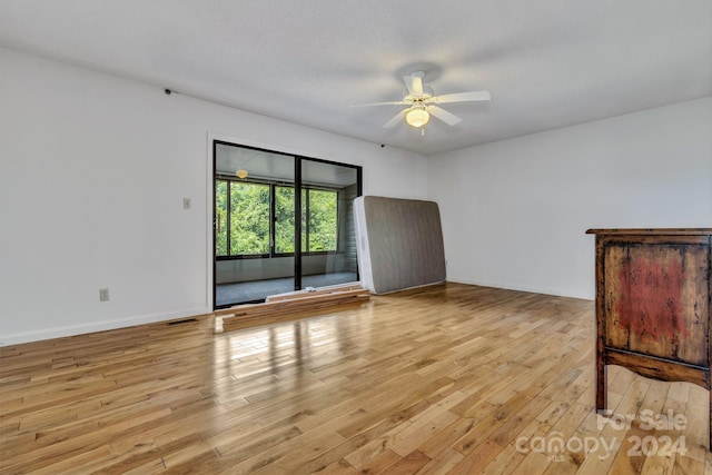 interior space with a ceiling fan, light wood-type flooring, visible vents, and baseboards