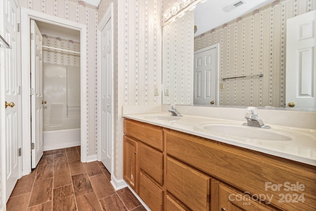 bathroom featuring visible vents, a sink, and wallpapered walls