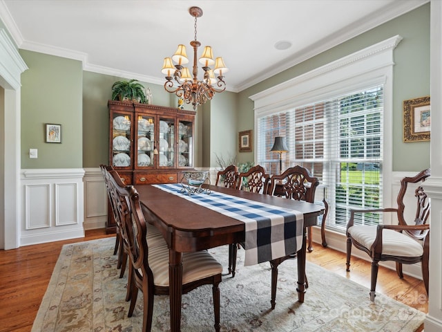 dining space featuring light hardwood / wood-style floors, ornamental molding, and a chandelier