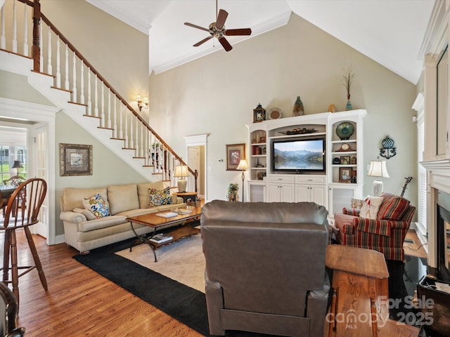 living room with ceiling fan, high vaulted ceiling, wood-type flooring, and ornamental molding