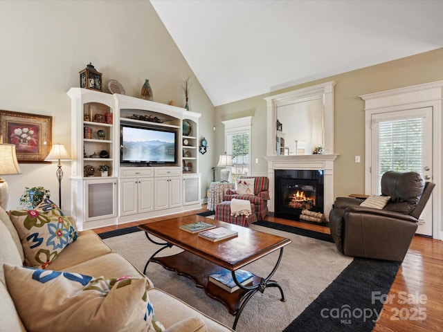 living room featuring high vaulted ceiling and light wood-type flooring