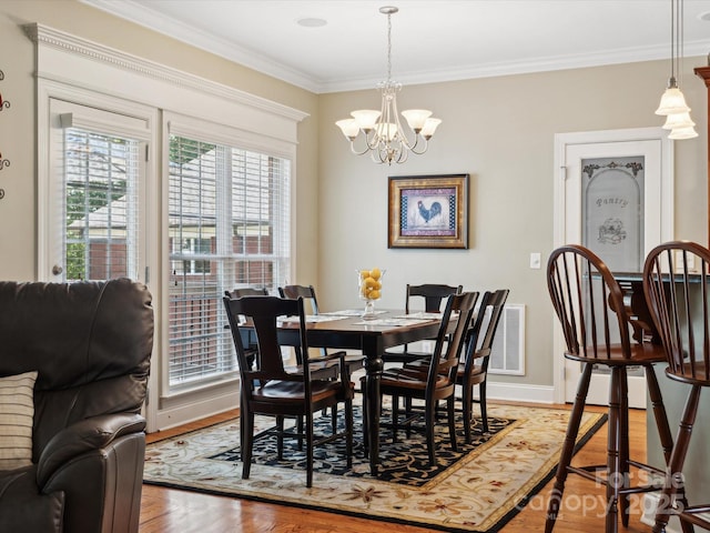 dining space featuring crown molding, hardwood / wood-style flooring, and a notable chandelier