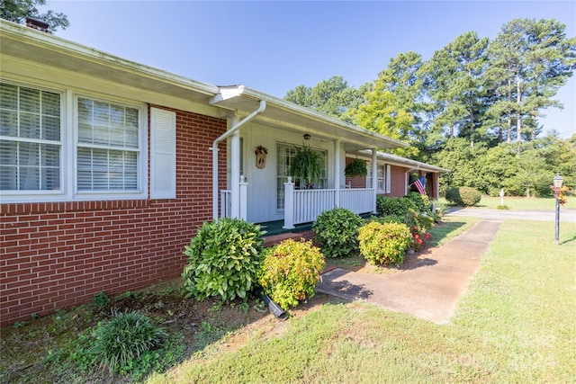 doorway to property featuring a yard and a porch