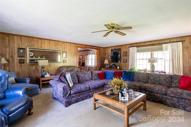 living room with ornamental molding, carpet, ceiling fan, and wood walls