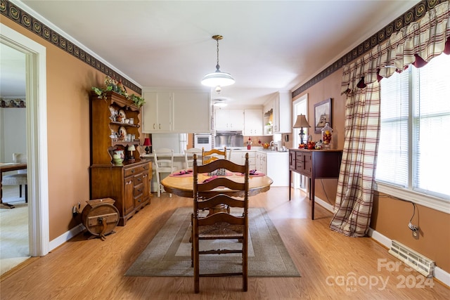 dining area with light wood-type flooring and crown molding