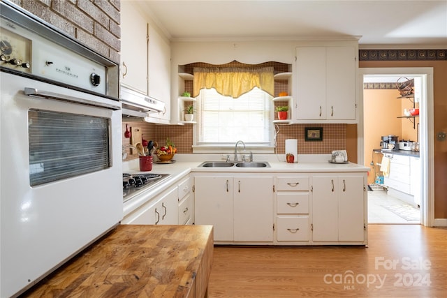 kitchen featuring light wood-type flooring, stainless steel gas stovetop, white cabinetry, and sink