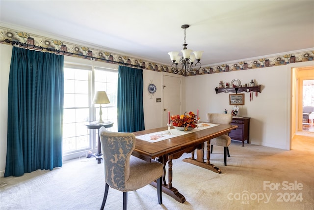 dining area with ornamental molding, plenty of natural light, an inviting chandelier, and light colored carpet