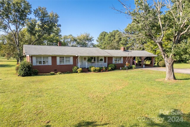 ranch-style home with a carport, covered porch, and a front yard