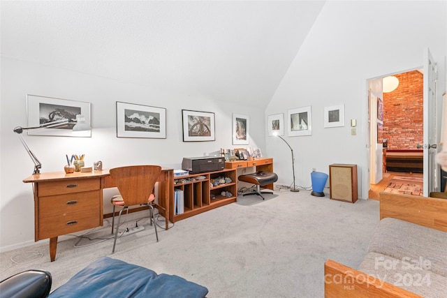 carpeted home office with brick wall and high vaulted ceiling