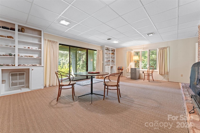 dining space with built in features, light carpet, and a drop ceiling