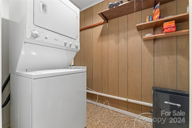 laundry area with stacked washer / dryer and wood walls